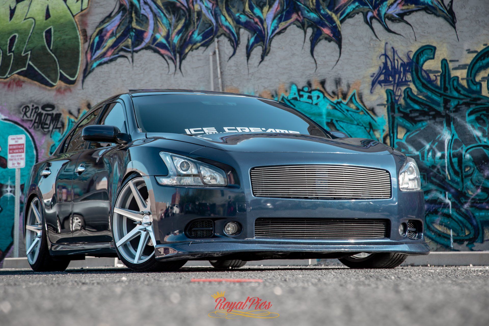 Modified dark gray sports car parked in front of colorful graffiti wall