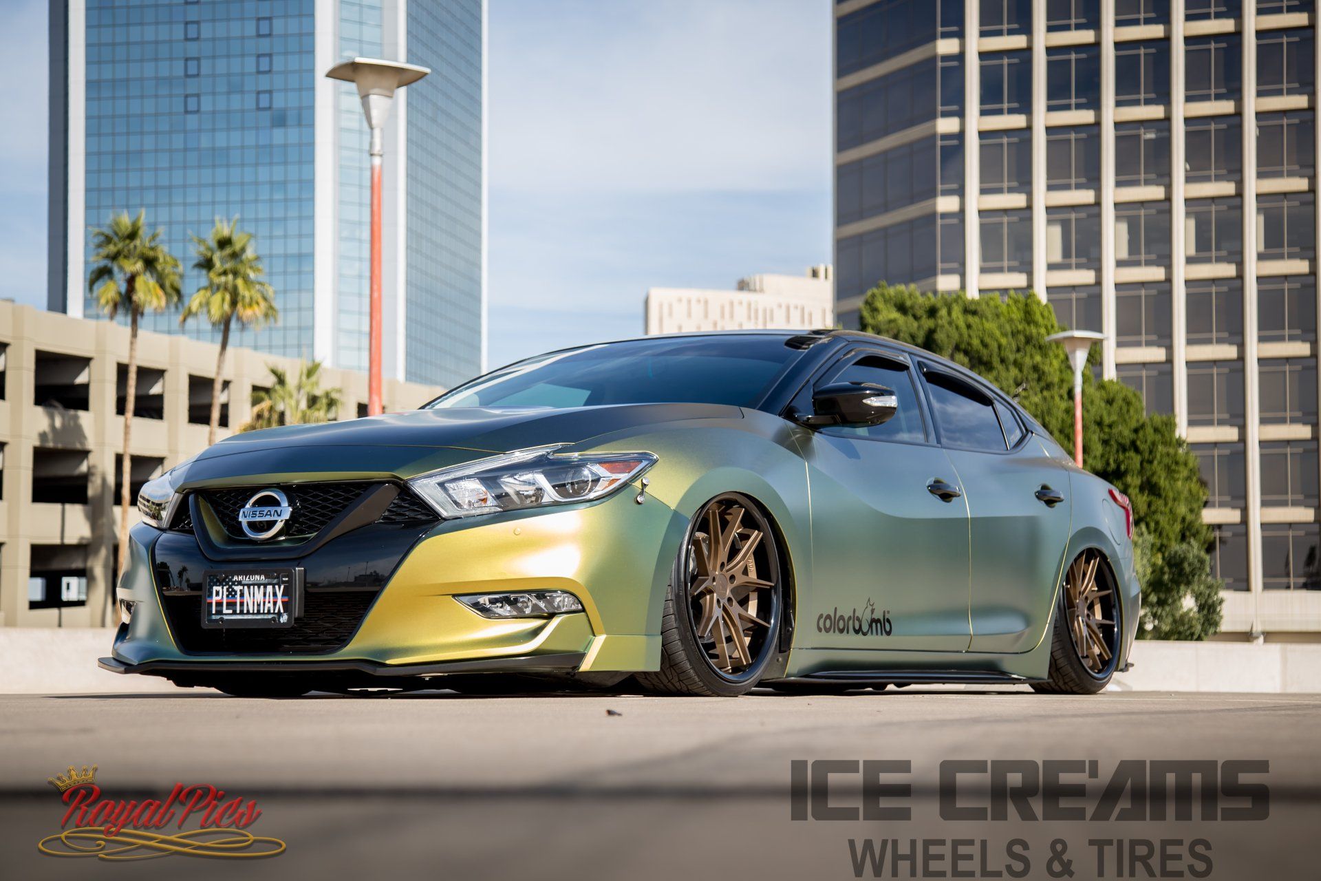 Custom black and gold Nissan parked downtown with lowered stance and bronze wheels