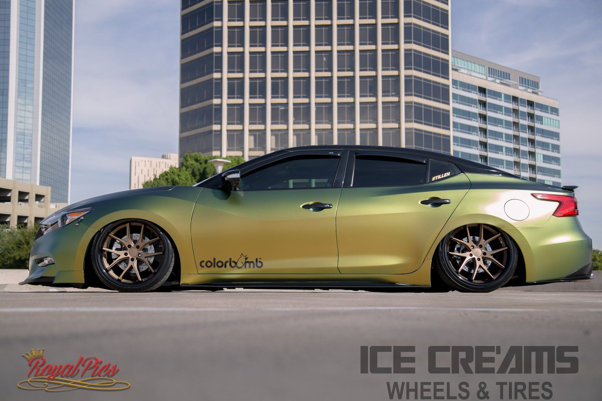 Green lowered sedan with black rims parked in front of a building, with tire shop logos visible.