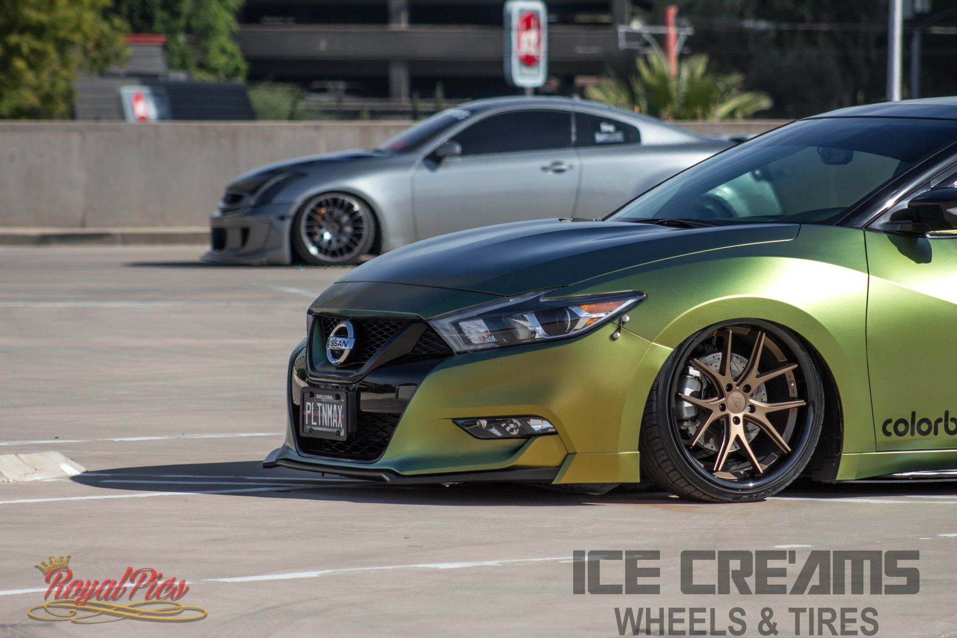 Two modified cars on a track, a green-and-gold sedan in front and a gray coupe behind, with wheels and tires branding.