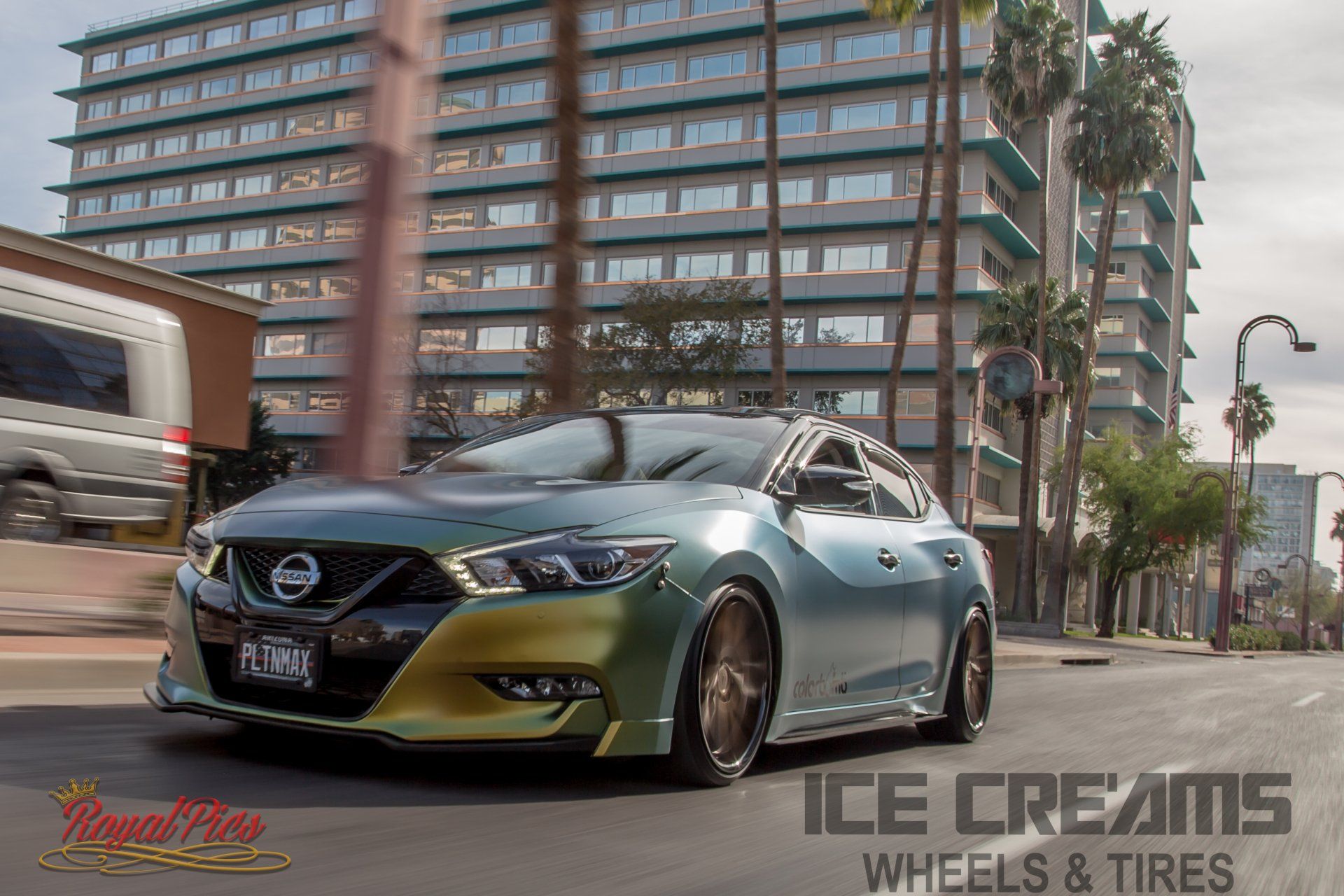 Customized green Nissan sedan driving on a city street with palm trees and apartment buildings