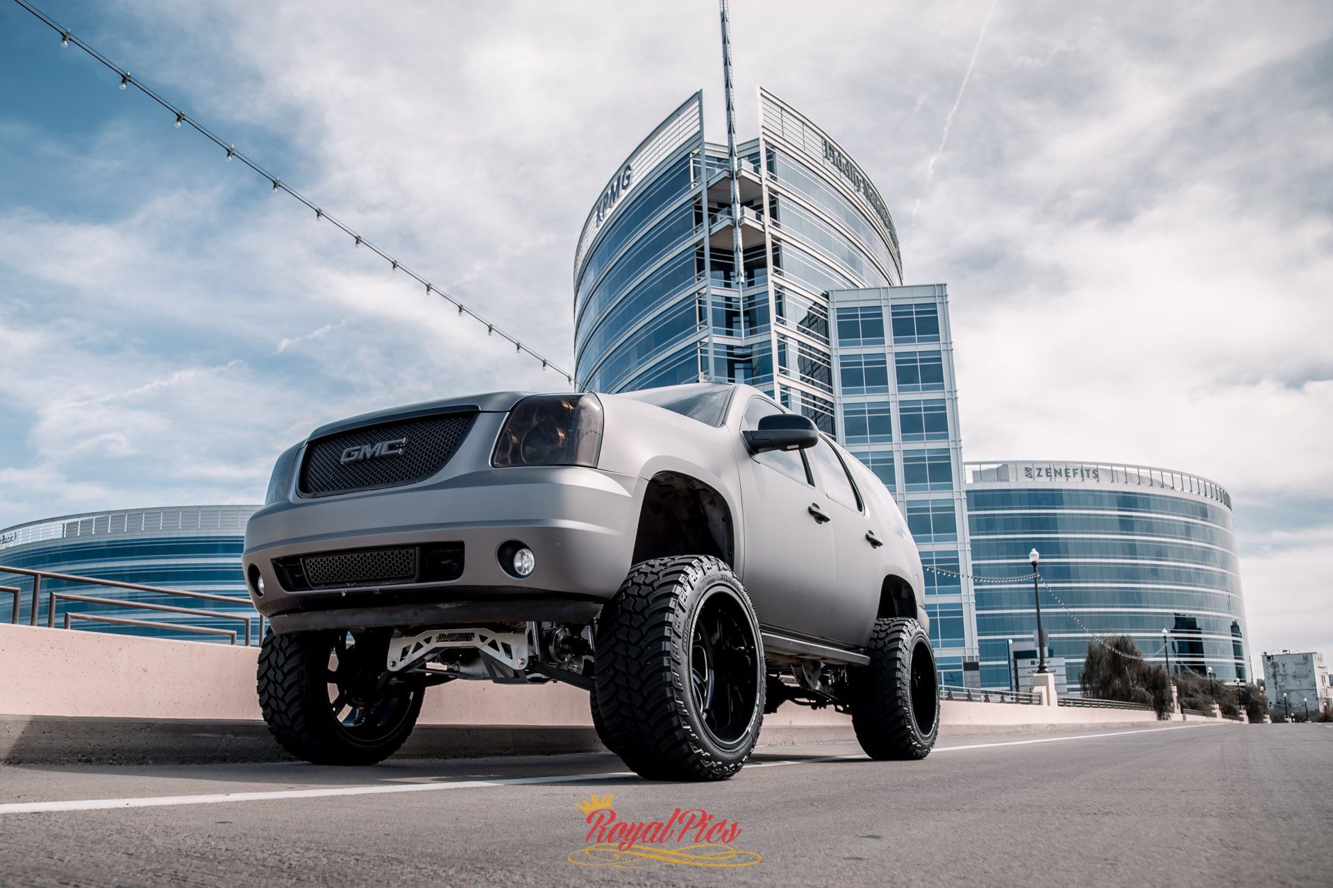 Custom lifted silver SUV parked in front of a modern glass building