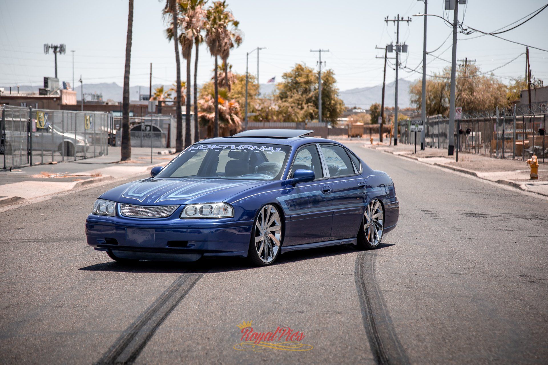 Blue sedan parked in the middle of a street with skid marks on the pavement