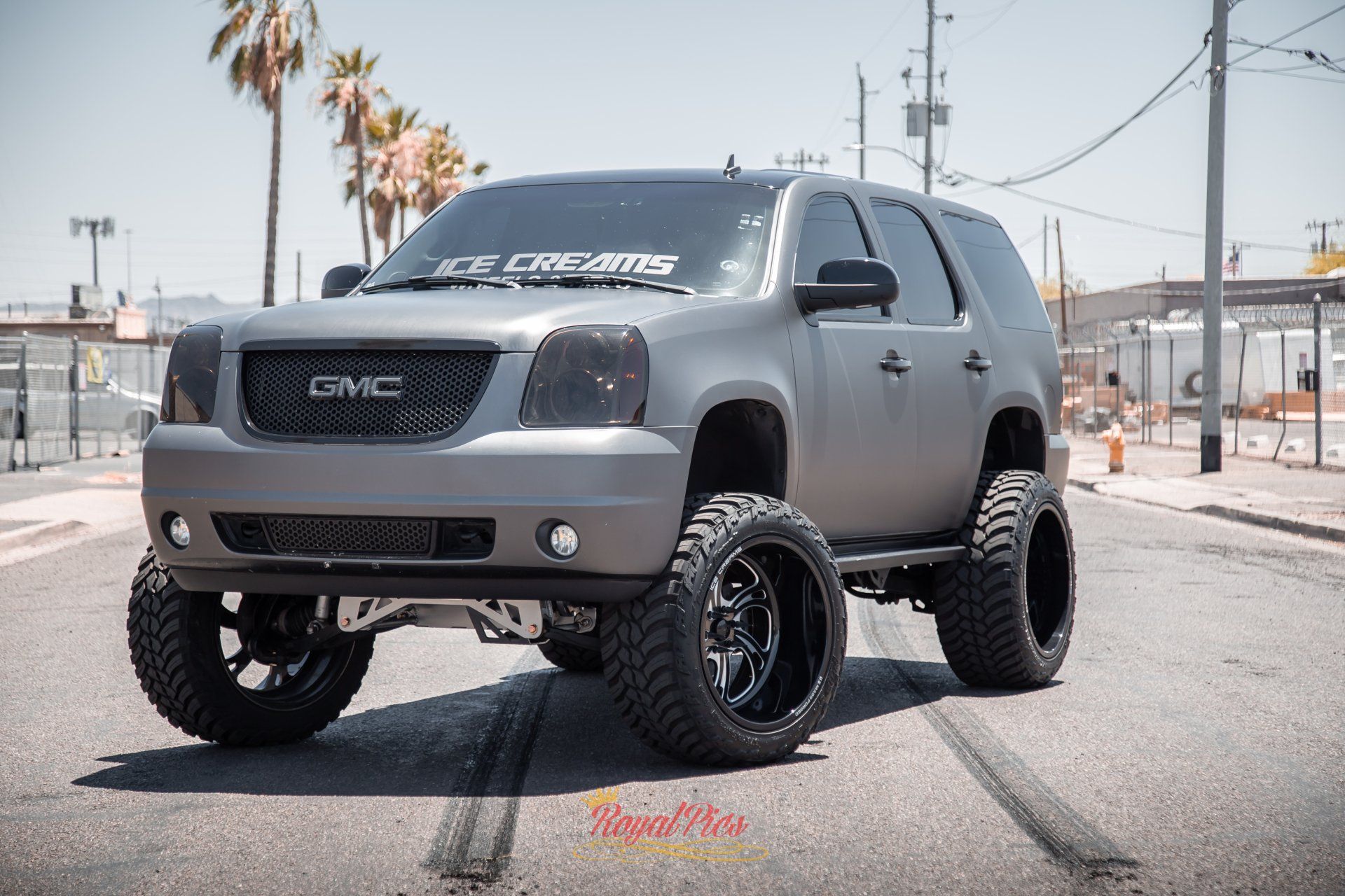 Gray lifted GMC pickup truck with oversized off-road tires parked on a street