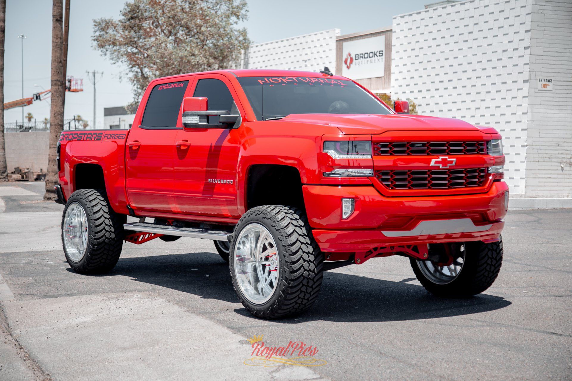 Red lifted pickup truck in bright red parked outdoors on pavement