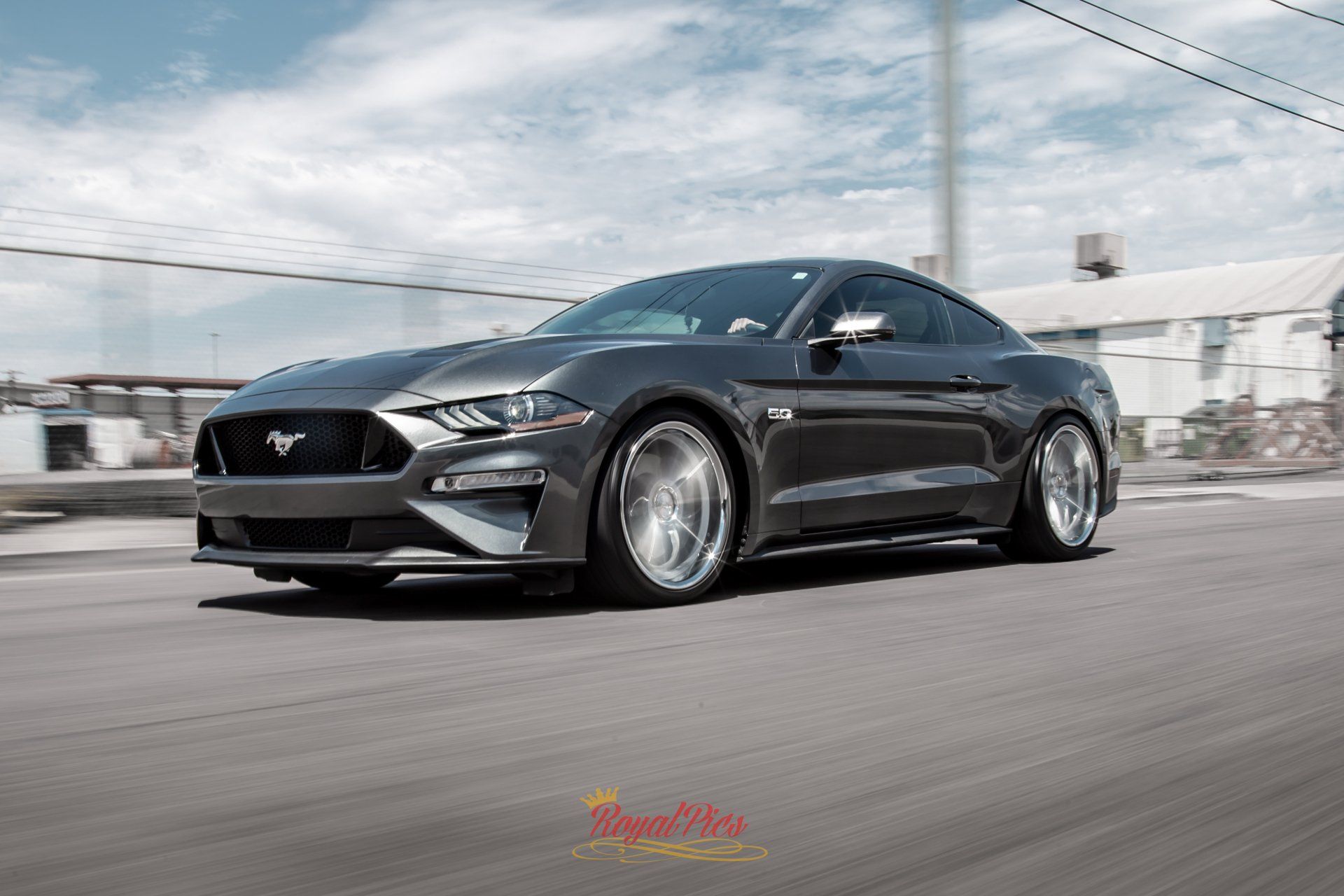 Black sports coupe driving on a road with motion blur and cloudy sky