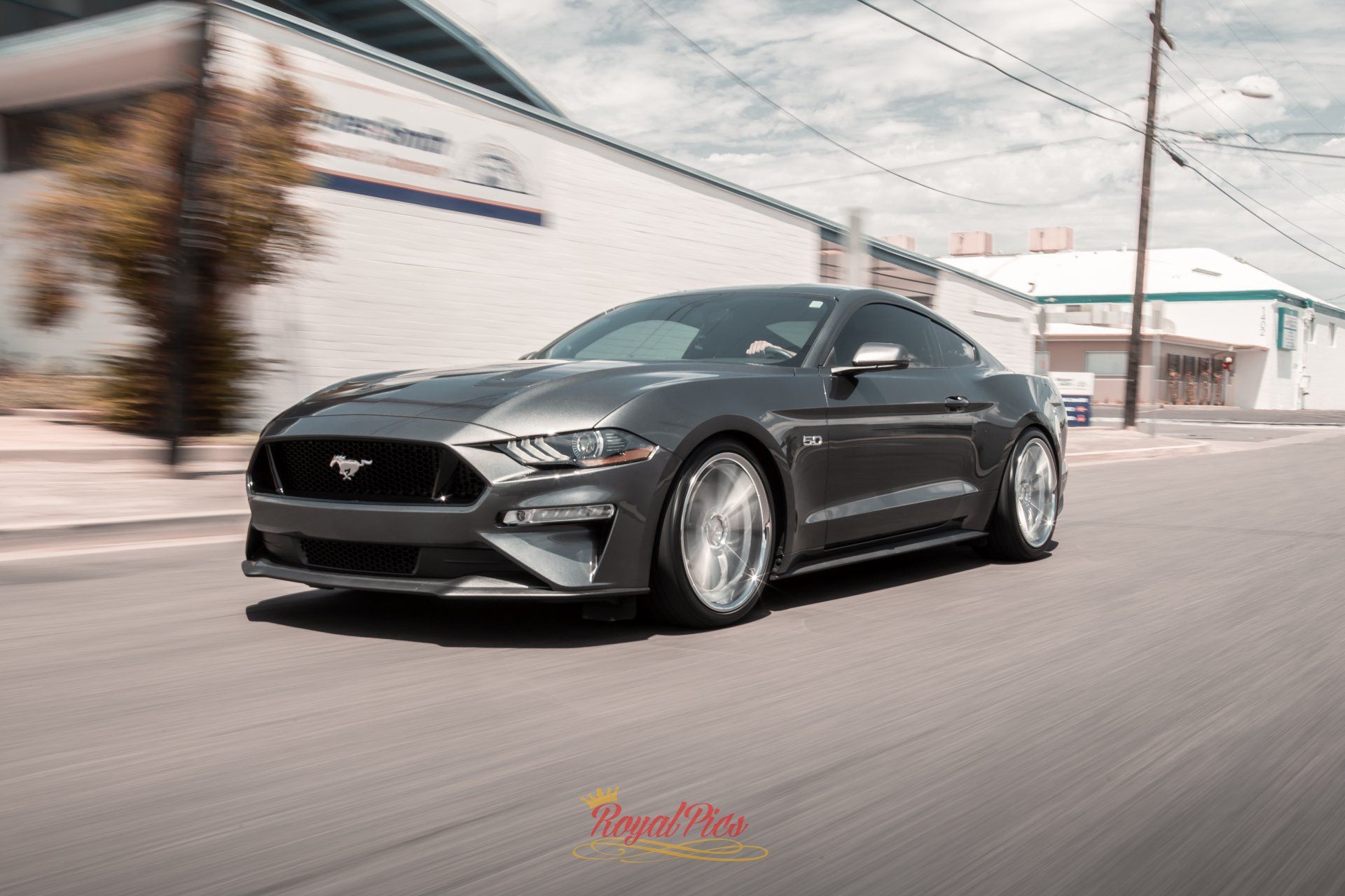 Black Ford Mustang driving on a city street, motion blurred background