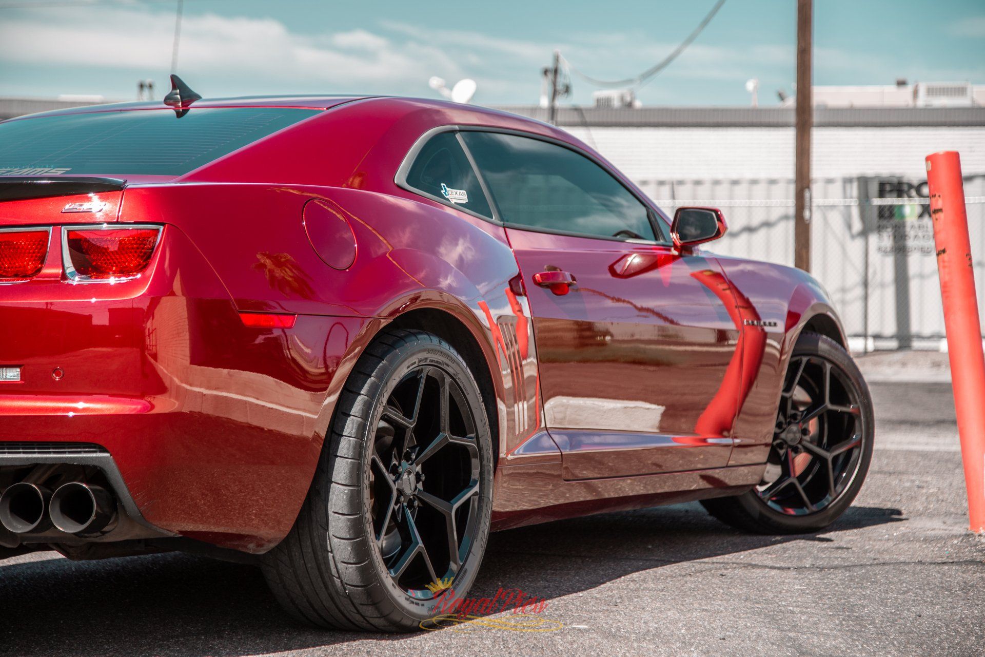 Red sports car parked outdoors, side view, with black wheels and orange accents.