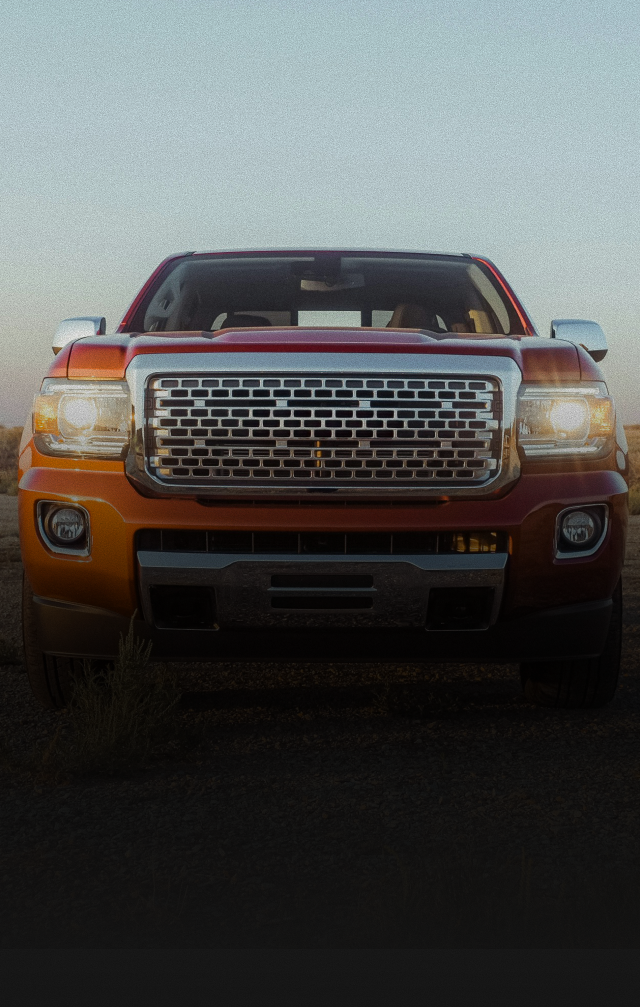 Orange pickup truck front view on a road at dusk