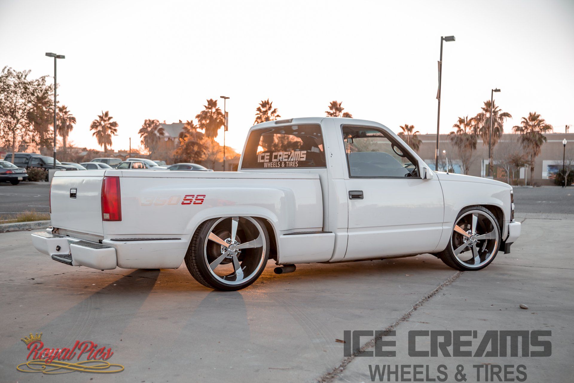 White lowered pickup truck with custom rims parked at sunset in a lot