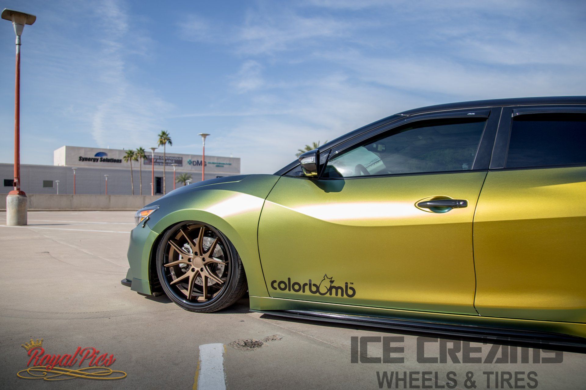 Yellow-green lowered sports car with bronze wheels parked outdoors on a rooftop lot