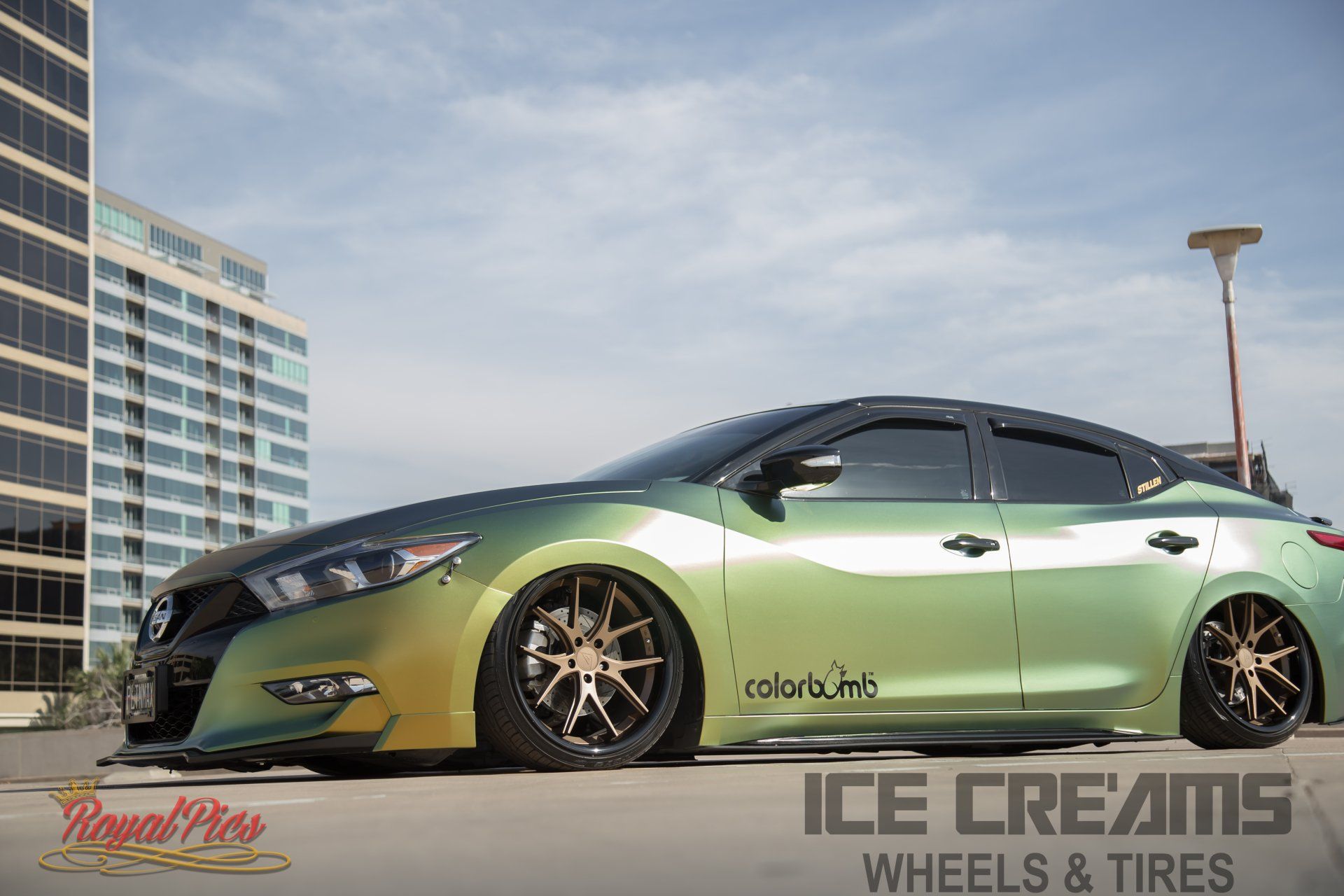 Green-and-black modified sedan parked outdoors with city buildings in the background, ICE CREAMS WHEELS & TIRES branding