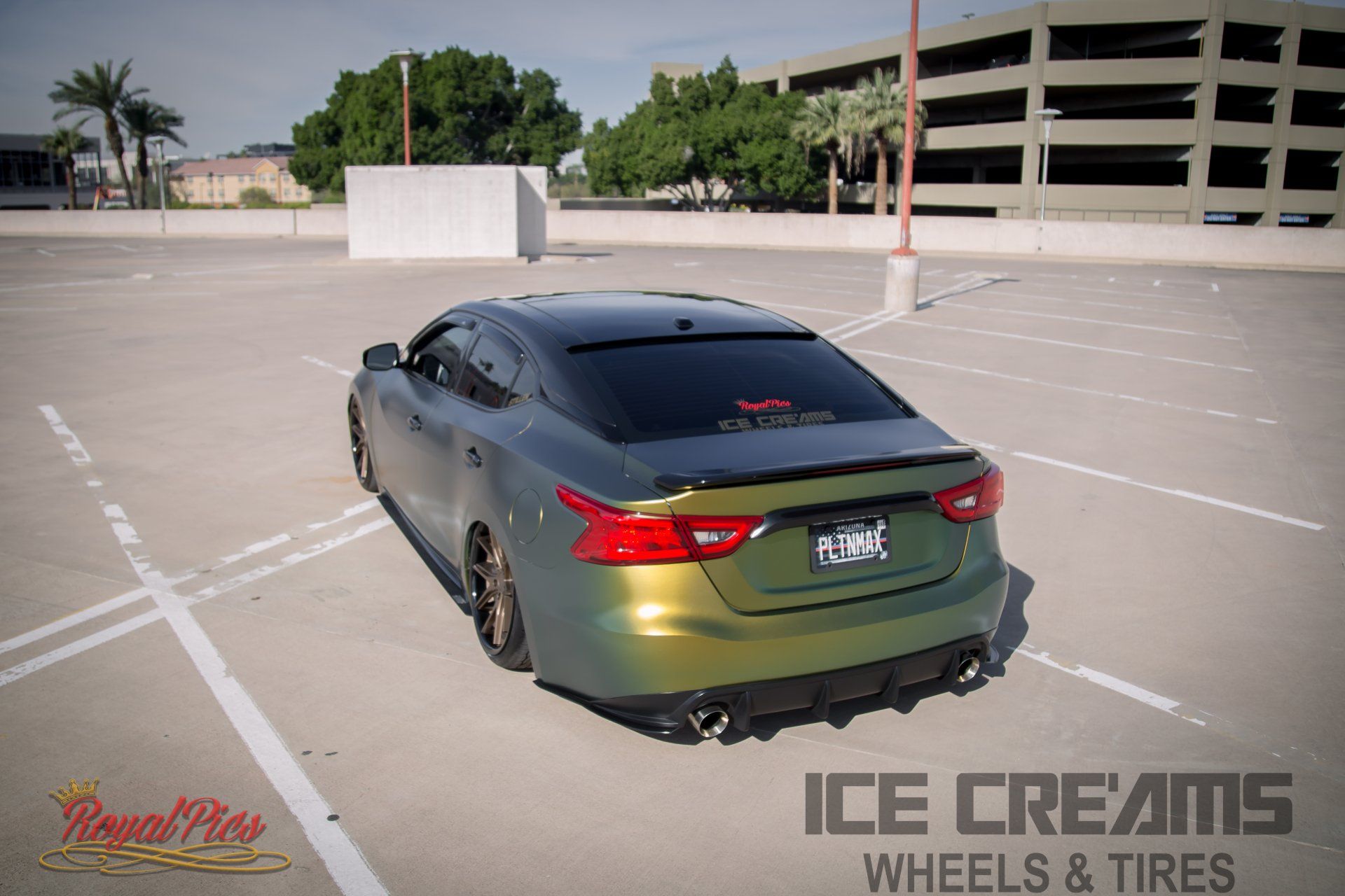 Green sedan with black roof parked in an empty rooftop lot under bright sun