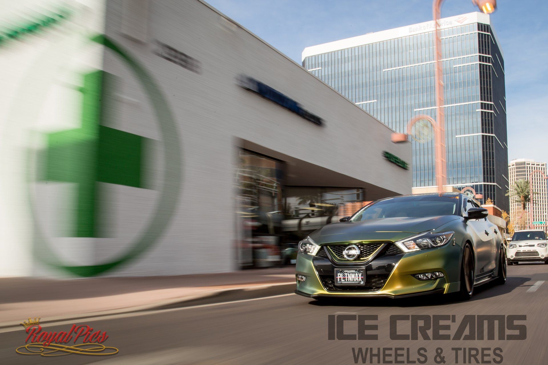 Green sports car driving past an ICE CREAMS Wheels & Tires storefront in a city street.