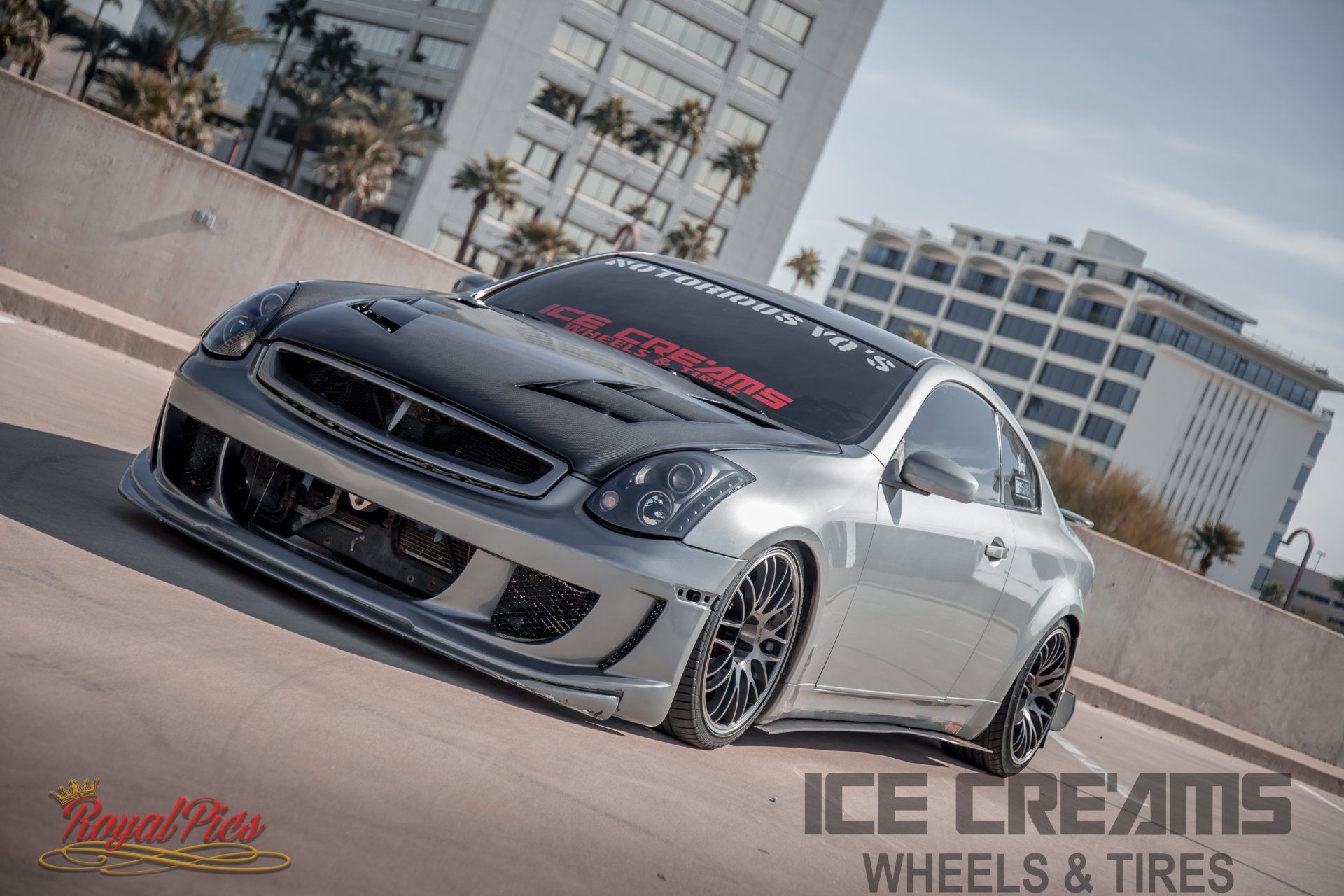 Customized silver sports car parked at an angle with city buildings in the background