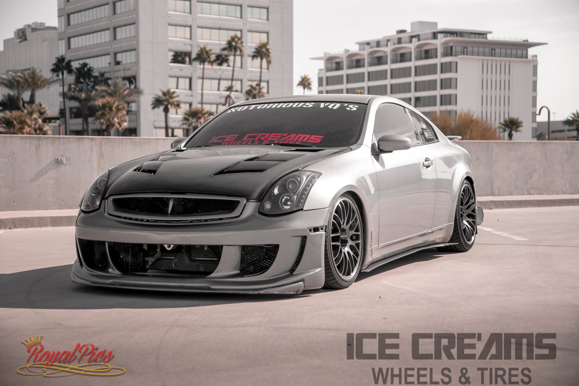 Gray modified sports car parked outdoors with city buildings in the background