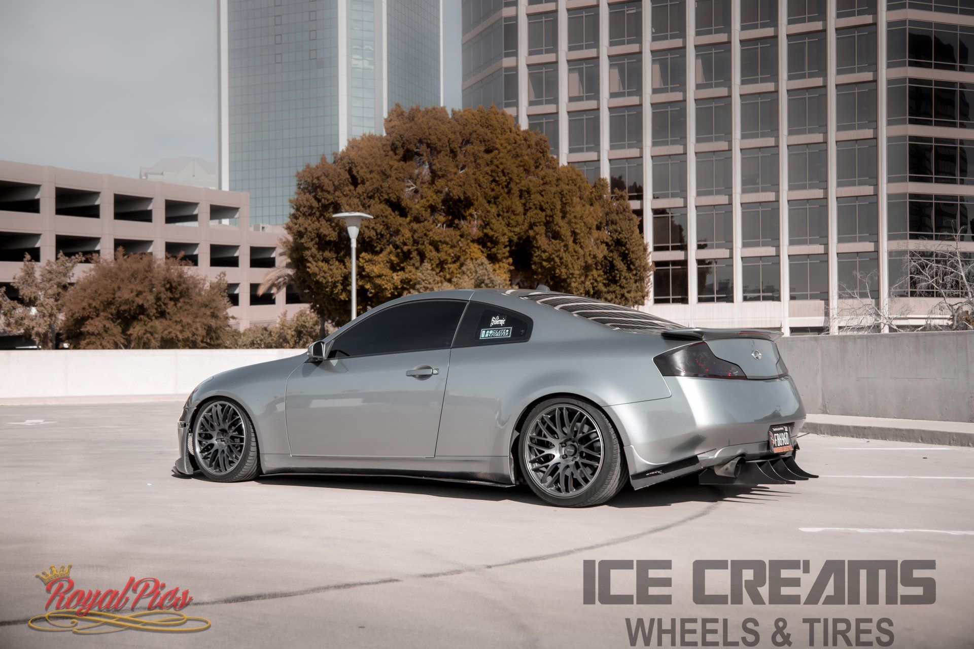 Silver lowered coupe parked in front of modern buildings with Ice Creams Wheels & Tires branding