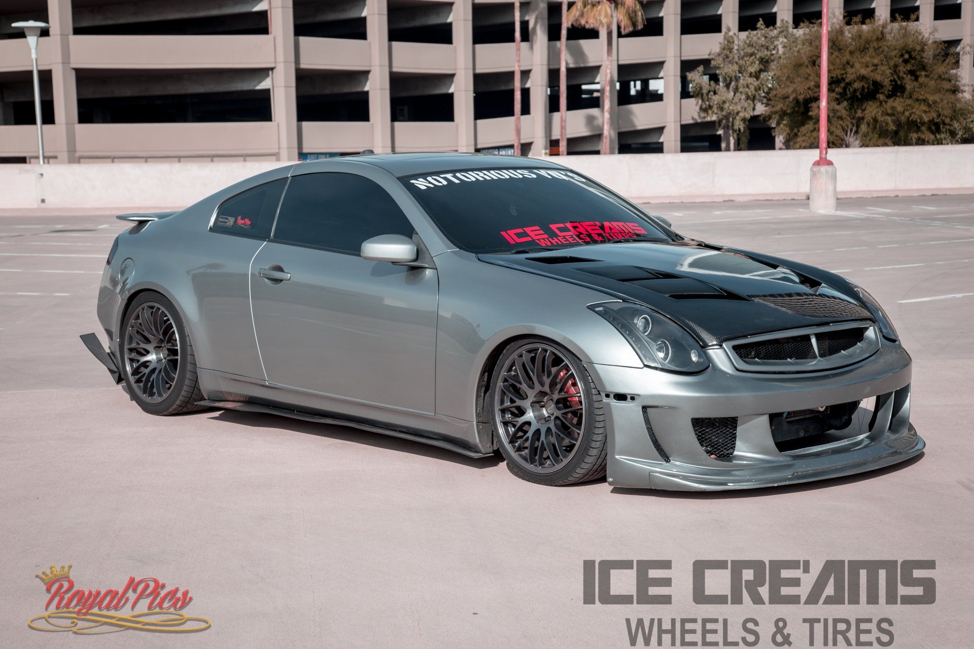 Gray modified coupe with black wheels, parked outdoors in front of a building, with ICE CREAMS WHEELS & TIRES logo.