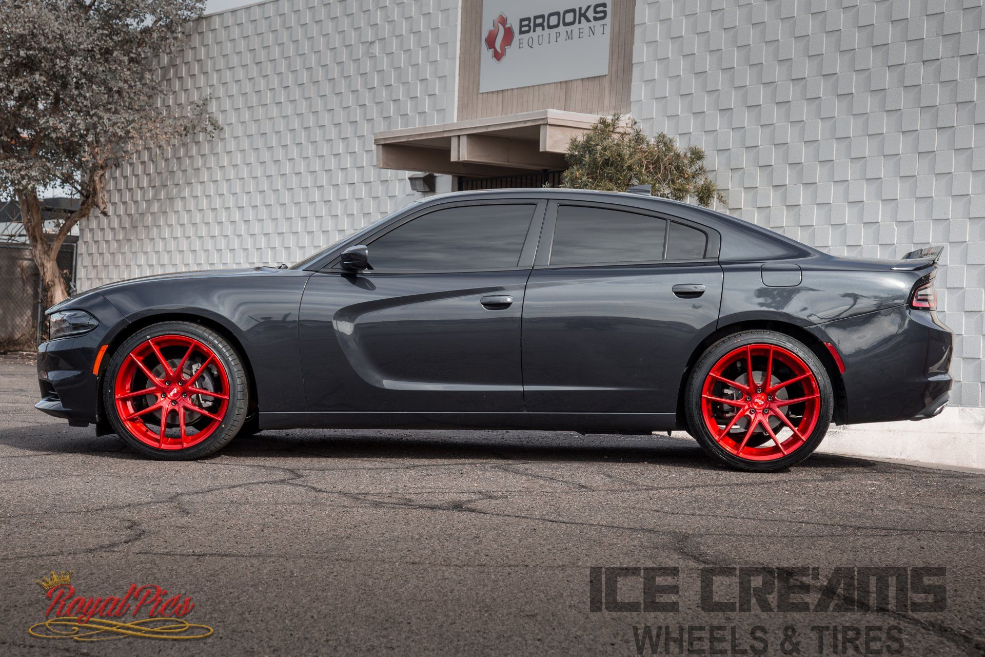 Gray sedan with red rims parked outside a wheel and tire shop