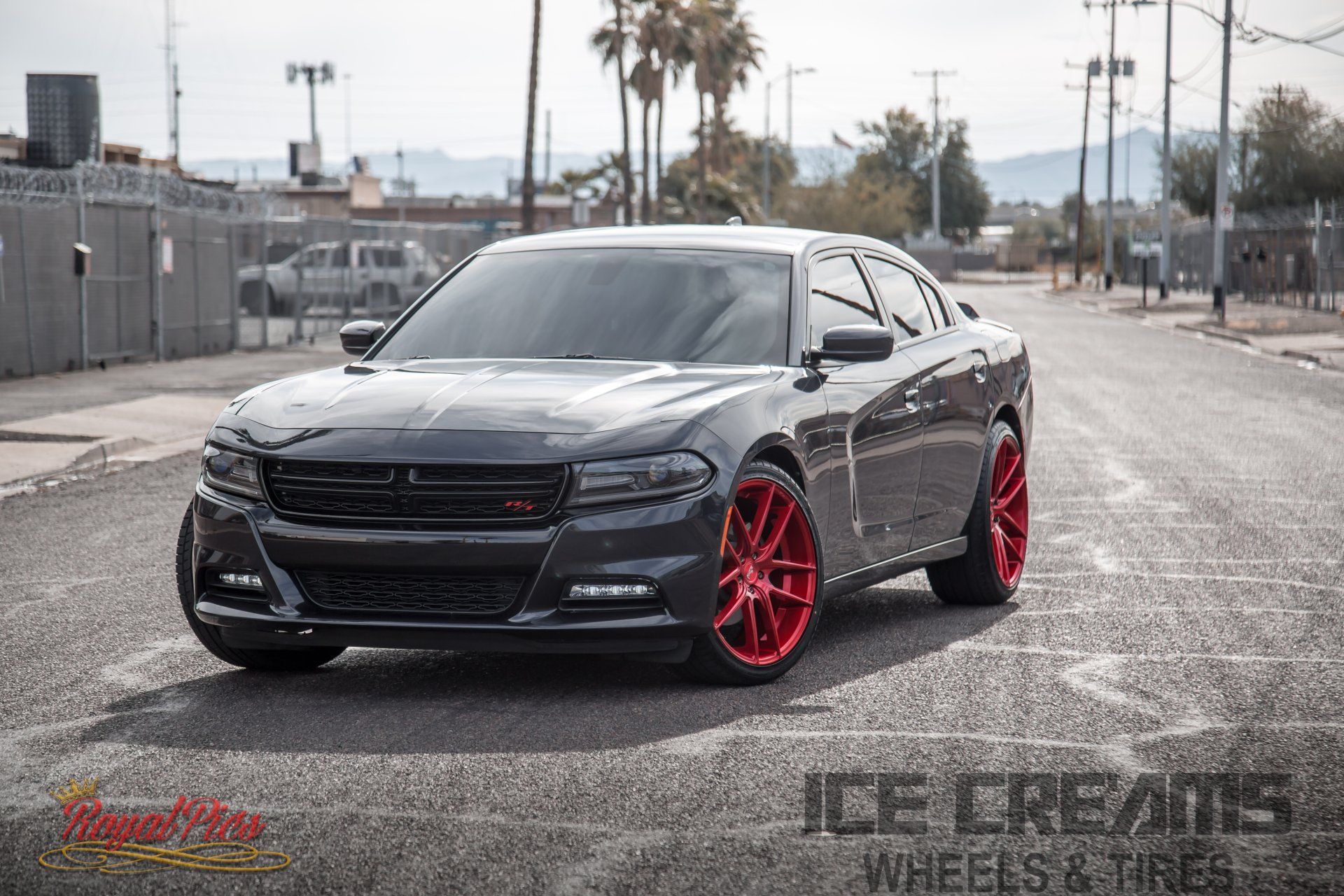 Black Dodge Charger with red rims parked on a street, angled front view