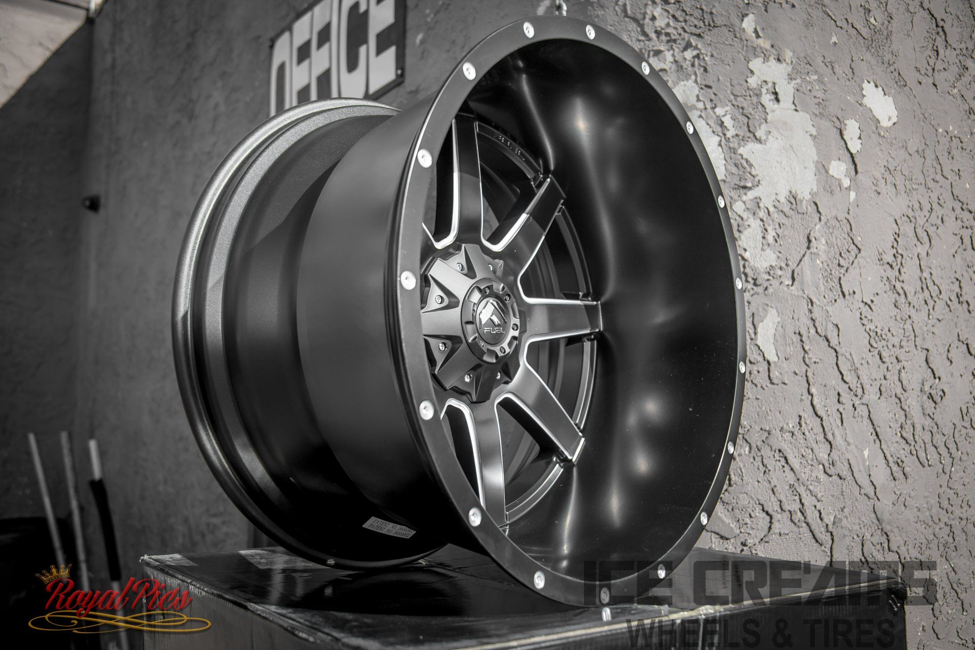 Gloss black deep-dish alloy wheel with multi-spoke rim on display against a textured wall