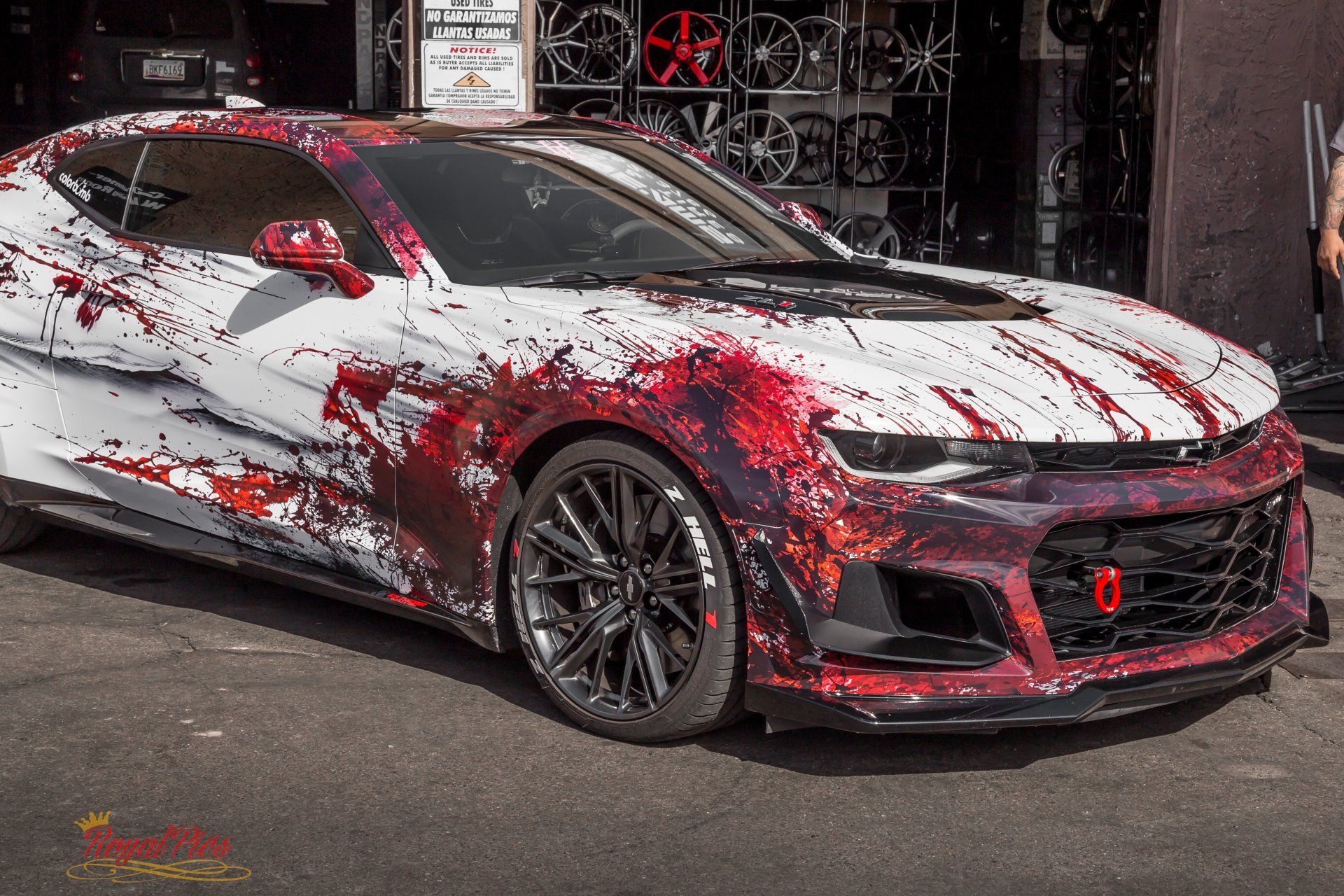 Modified white sports coupe with red splatter paint parked on a street