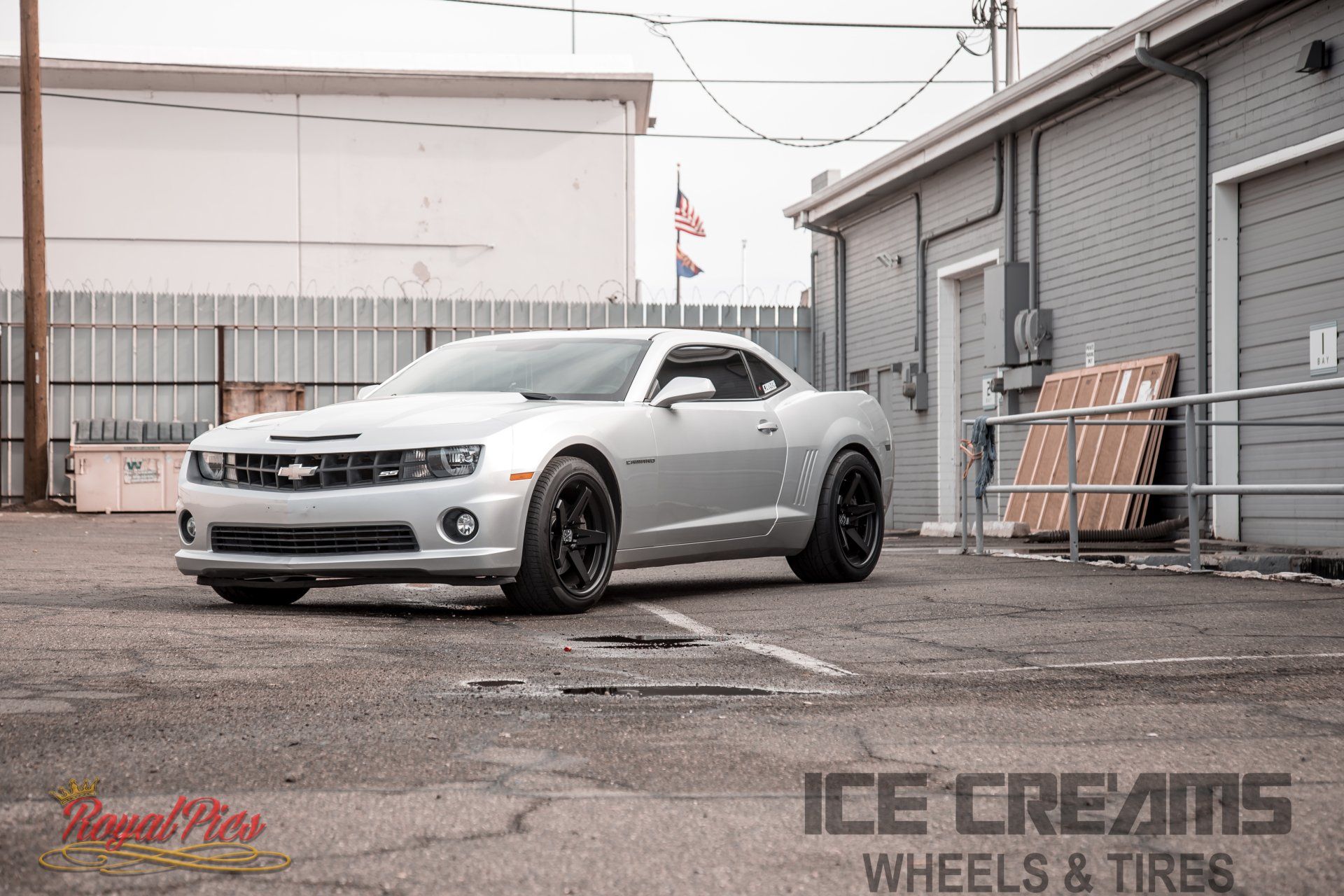 Silver sports coupe parked in an industrial lot with black wheels and lowered stance