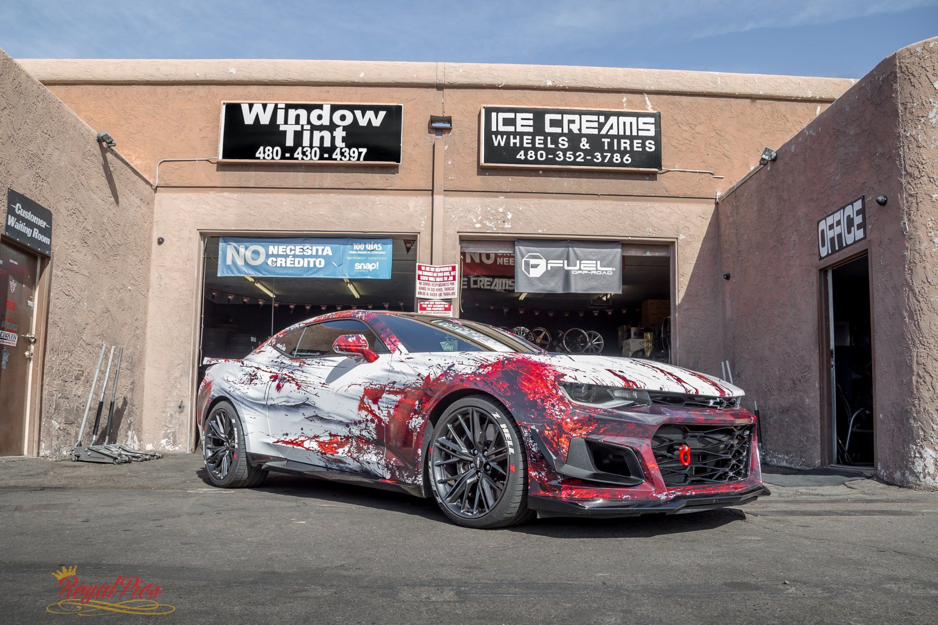 Modified silver sports car with red graphics parked outside a window tint and ice cream shop