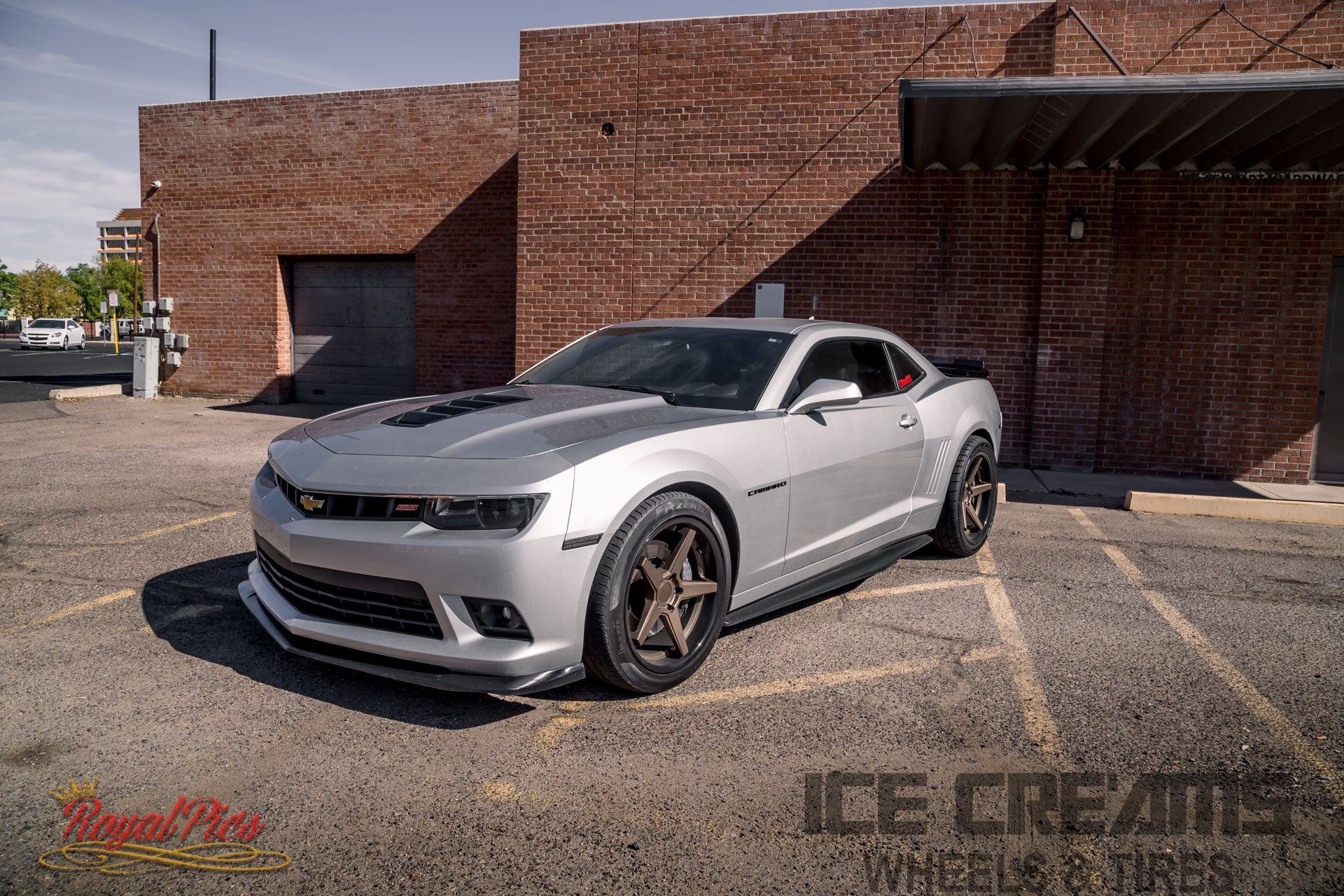 Silver sports car parked outside a brick building in bright sunlight