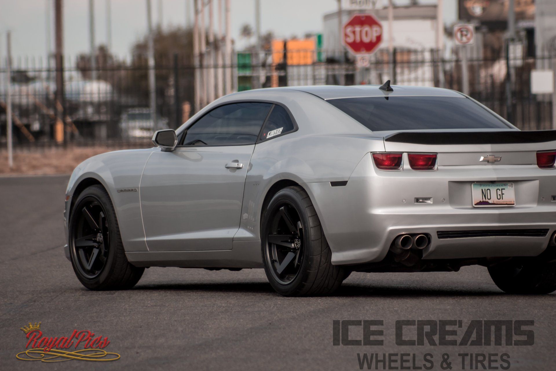 Silver Chevrolet Camaro parked outdoors with black wheels and tinted windows at dusk