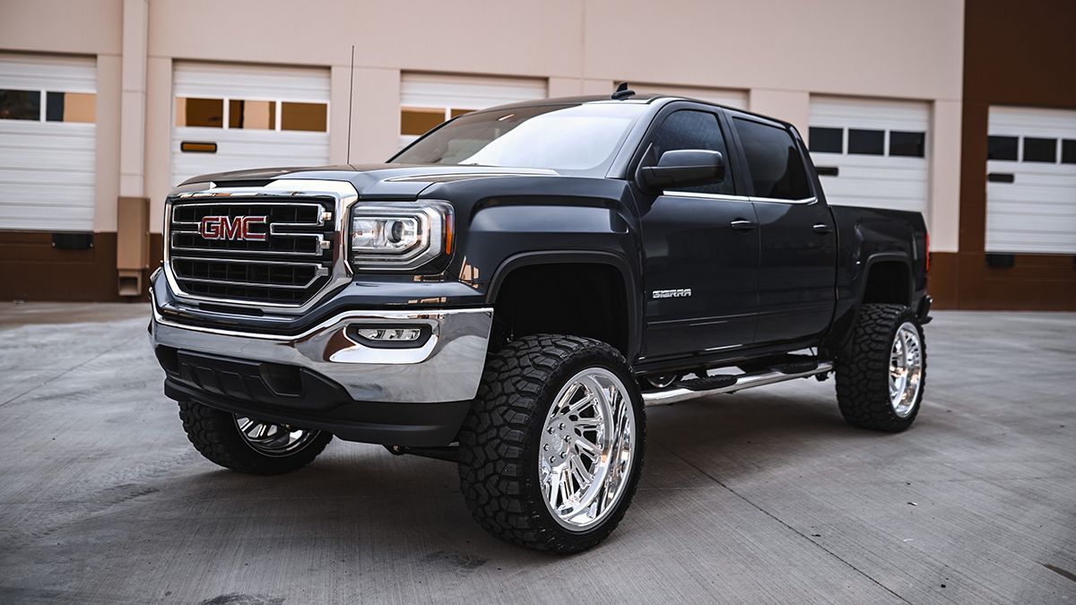 Black GMC pickup truck parked in front of a garage, angled view