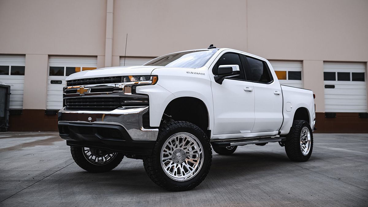 White lifted pickup truck parked outside a building