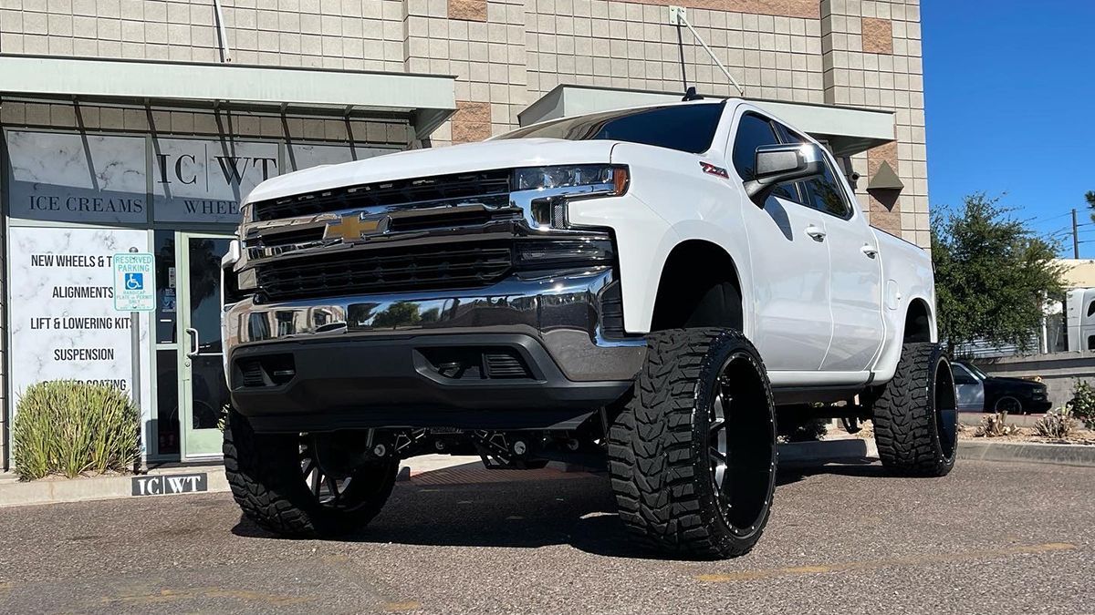 White lifted Chevrolet pickup parked outside a building on a sunny day