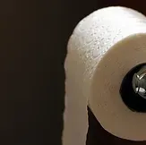 White toilet paper roll on a holder against a dark background