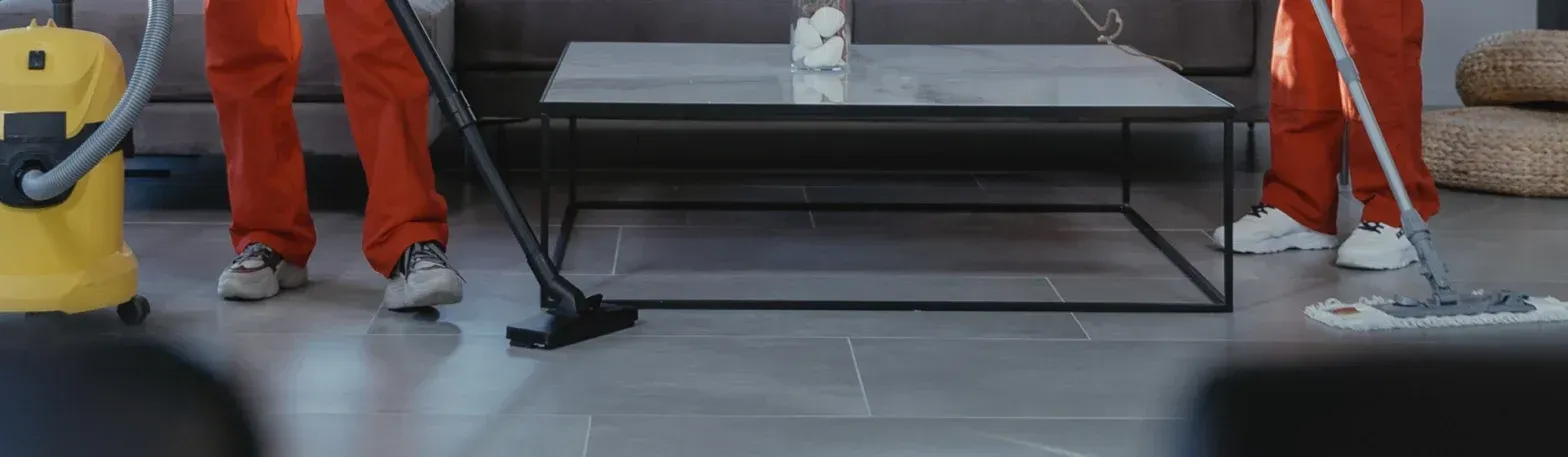 People in orange pants standing around a black glass coffee table with metal legs in a living room