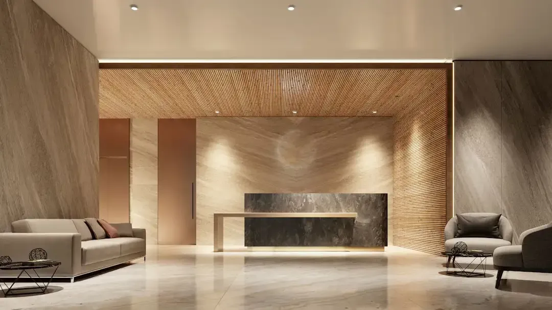 Modern commercial lobby with polished stone floors, wood accents, and a contemporary reception desk.