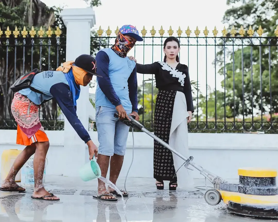 Cleaning crew using a floor scrubber to clean an outdoor commercial walkway.