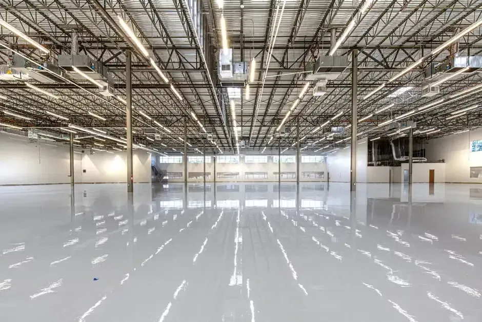 Ride-on floor scrubber cleaning a large concrete warehouse floor