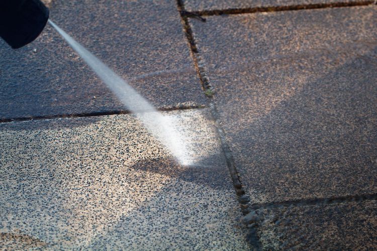 Water spraying onto a gray shingled roof or pavement, creating a bright splash. Water spraying onto a gray shingled roof or pavement, creating a bright splash.