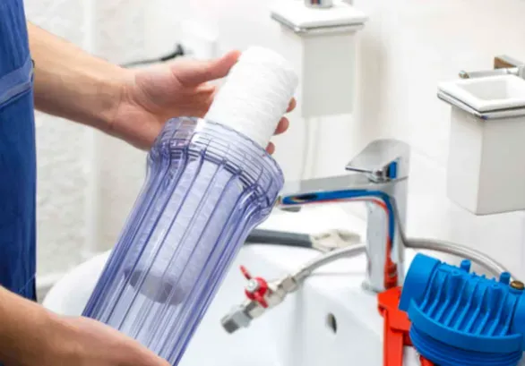 A person is holding a water filter in front of a sink.