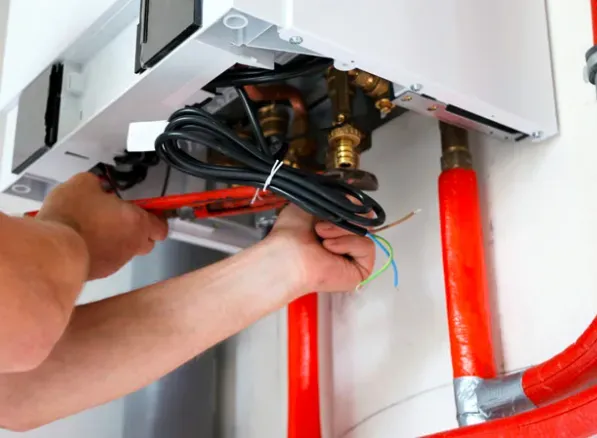 A man is fixing a boiler with a wrench.