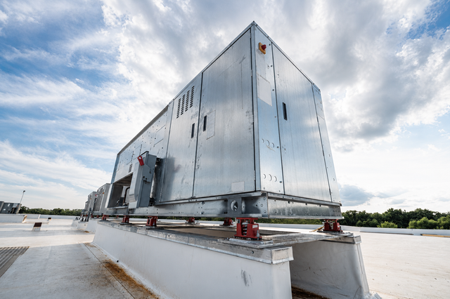 Large silver industrial container on a rooftop platform under a cloudy sky