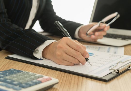 a person in a suit writing on a piece of paper