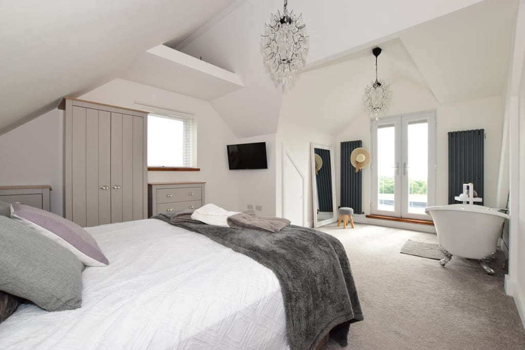 A bedroom with a large bed and a bathtub.