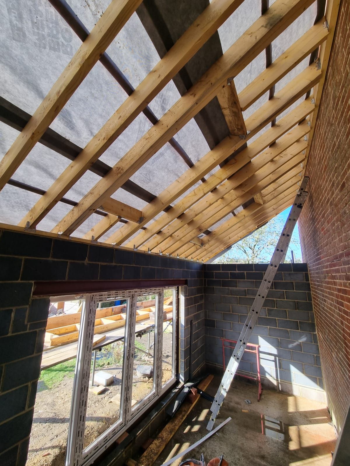 A room under construction with a wooden roof and a ladder.