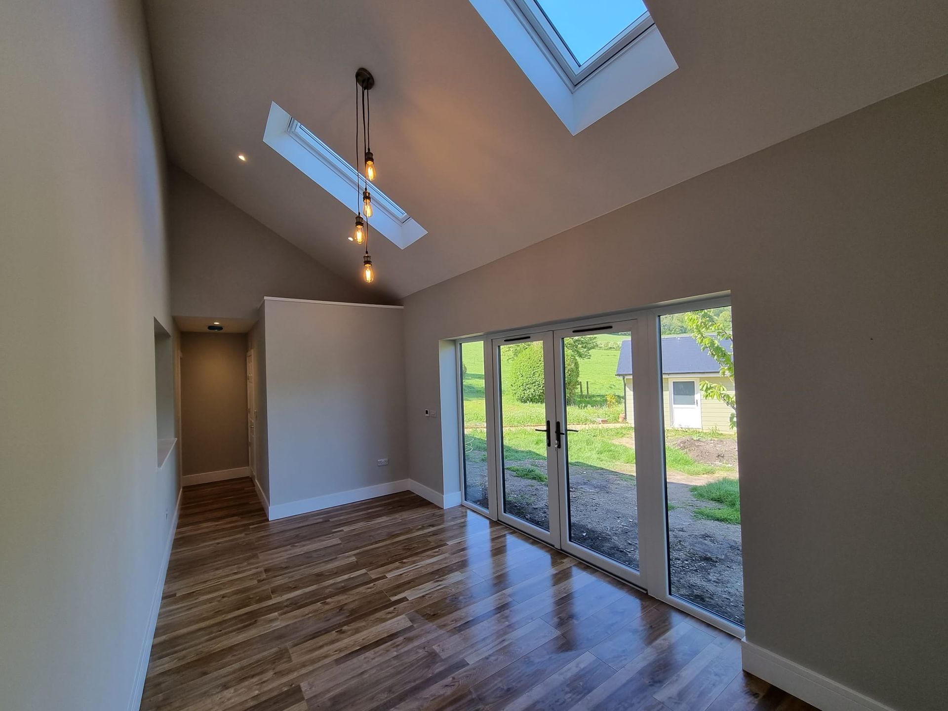 An empty room with hardwood floors and a skylight in the ceiling.