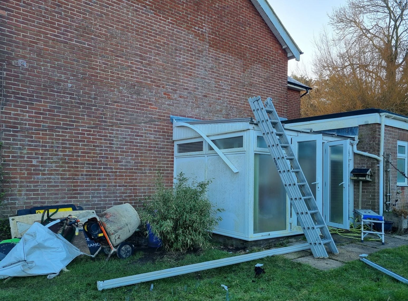A ladder is sitting in front of a brick building.