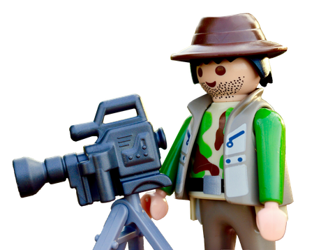 A playmobil figure is holding a camera on a tripod