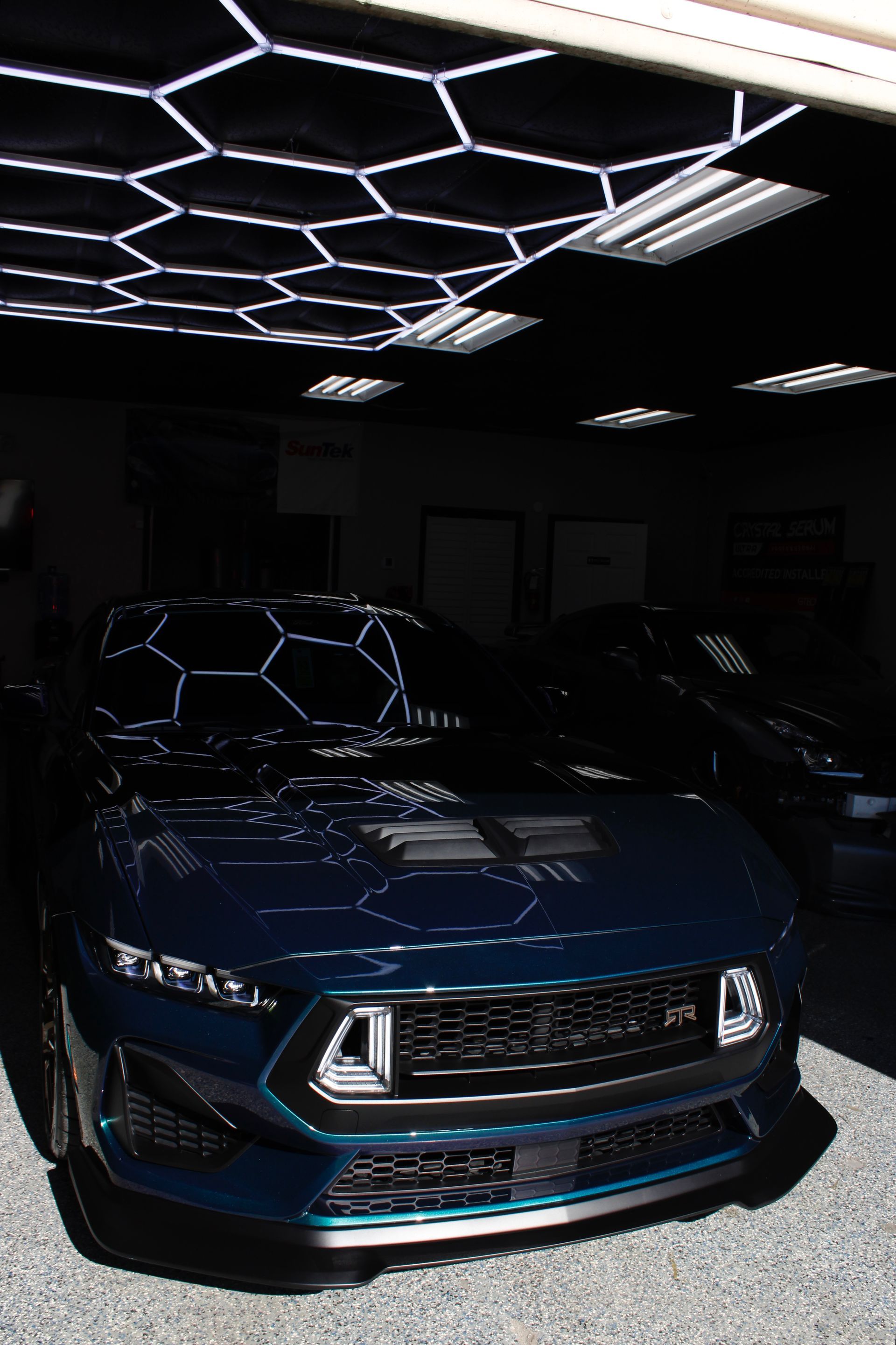 Blue sports car in a dark showroom under geometric ceiling lights