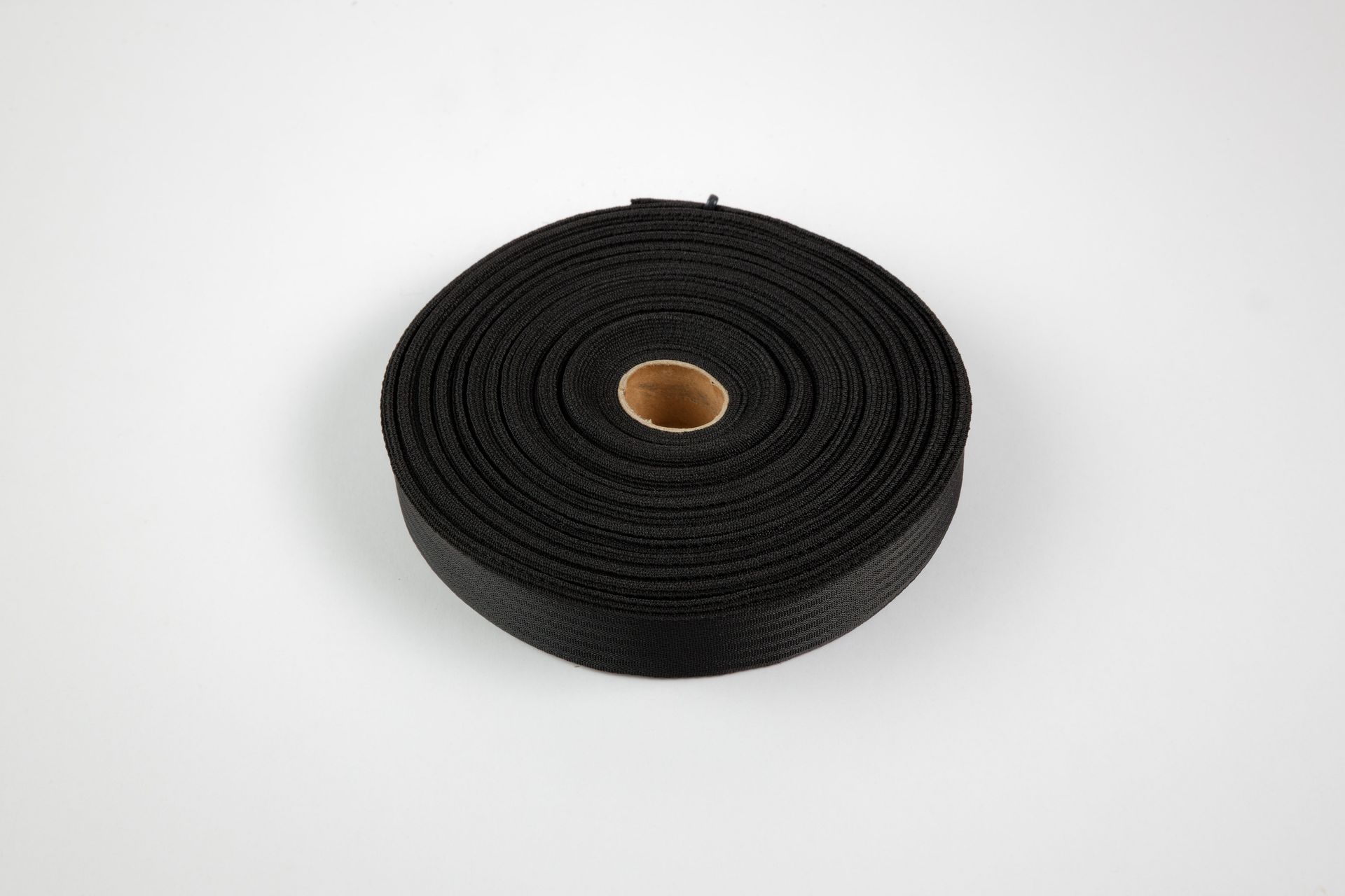 A roll of black tape with a hole in the middle on a white surface.